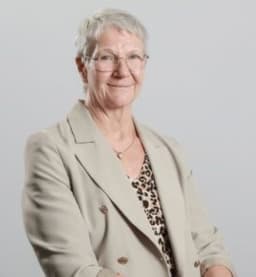 Woman in a beige blazer, smiling at the camera
