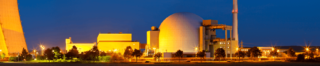 Nuclear power station with domed reactor building and adjacent structures lit up at dusk
