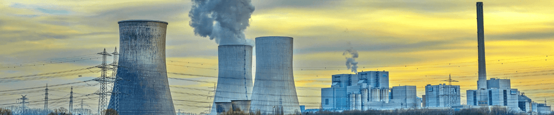 Cooling towers and industrial buildings of a power station with steam rising against a cloudy sky